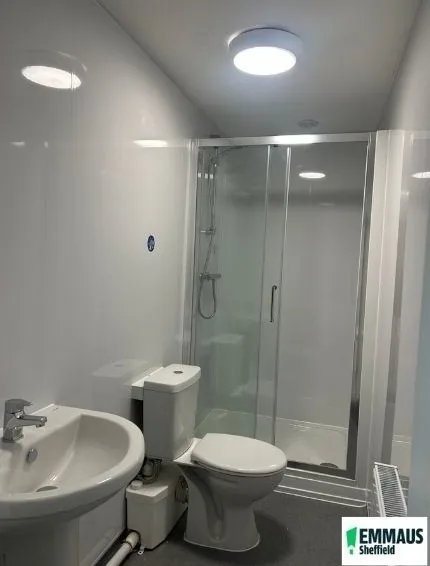 Newly fitted shower room with white wall panelling, a glazed shower enclosure, toilet and basin