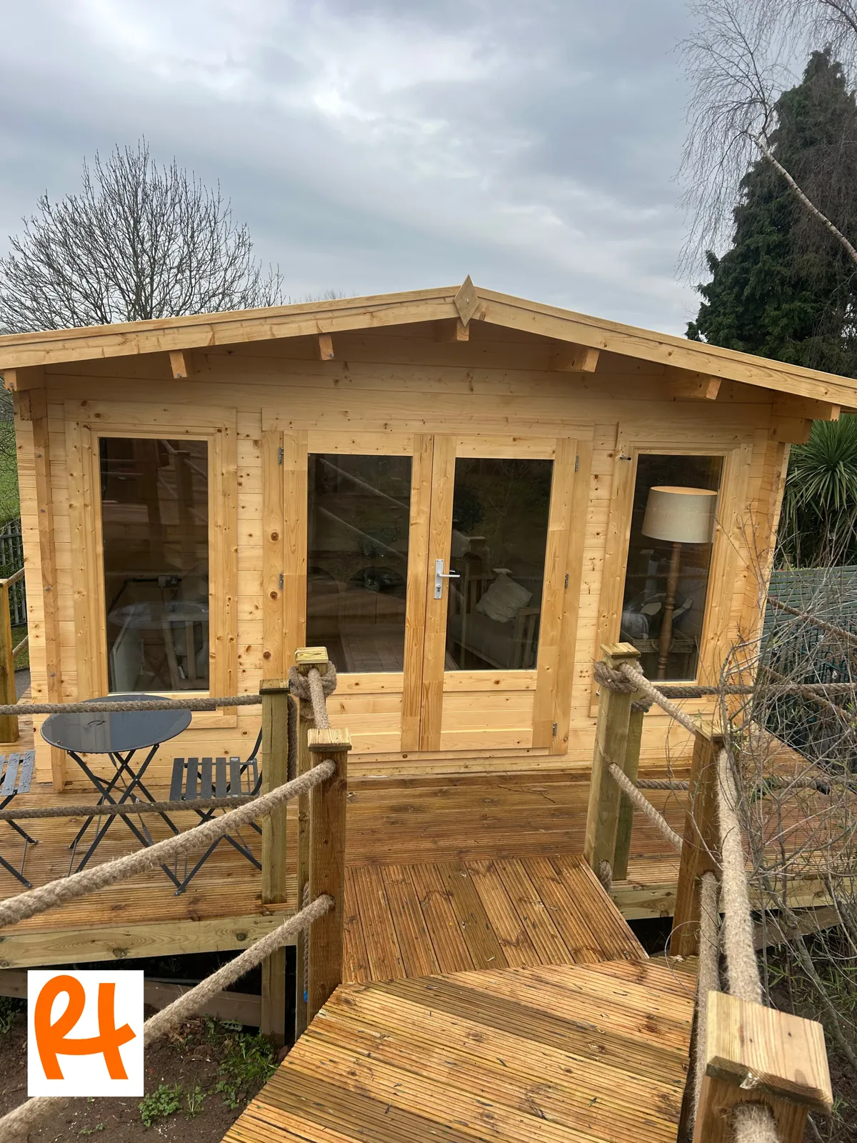 Timber garden room with glazed double doors, opening onto new decking with rope-lined balustrades